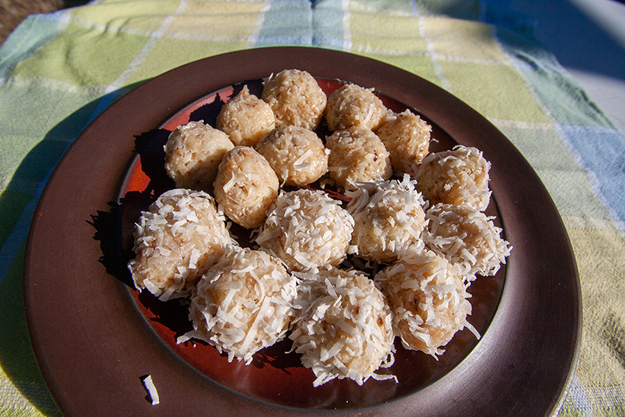 16 coconut ladoos, the Indian dessert. Balls made of shredded coconut and sweetened condensed milk. Half are covered in shredded, sweetened coconut, the other half are plain.